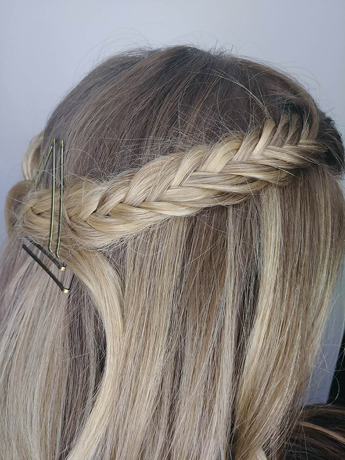 Side view of a person's head showing a styled braid with hairpins in straight blond hair. - K. Charles & Co. in San Antonio and Schertz, TX