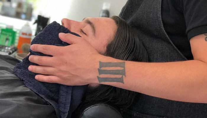 A barber covers a client's face with a hot towel during a waxing session in a salon. - K. Charles & Co. in San Antonio and Schertz, TX