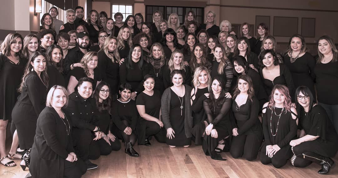 A large group of people in black attire posing for a photo in a spacious room. - K. Charles & Co. in San Antonio and Schertz, TX