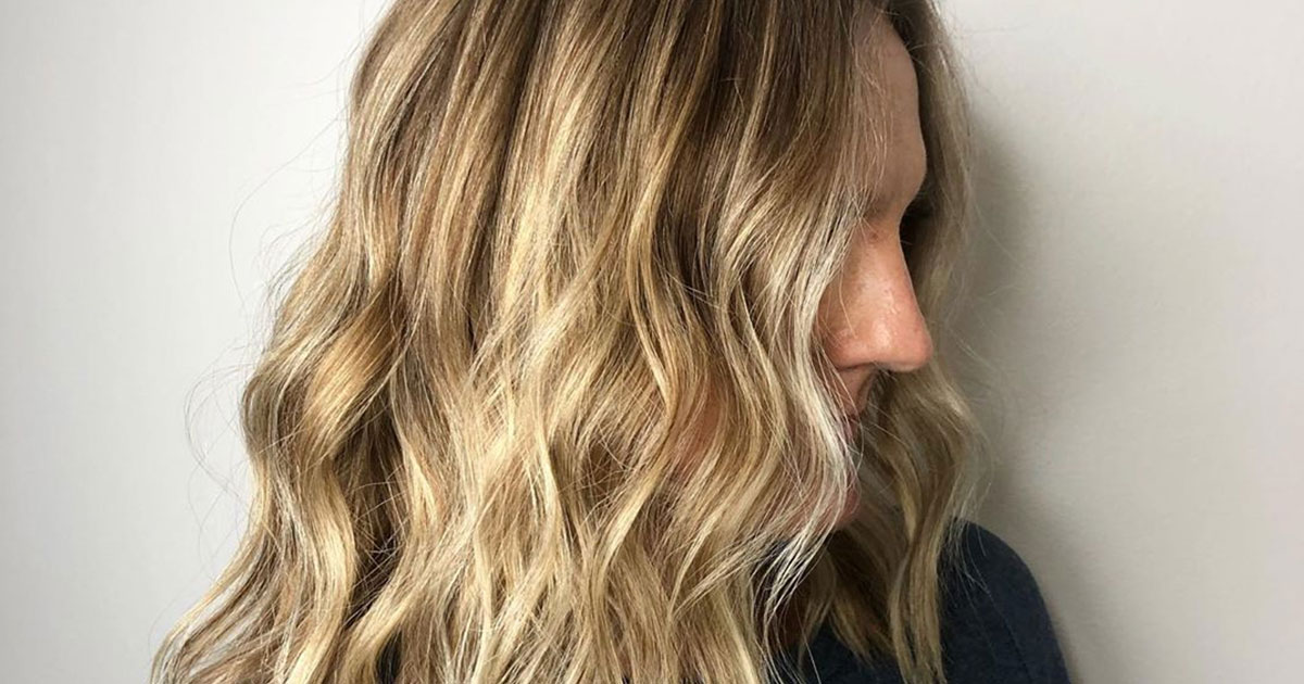 Profile view of a person with long, wavy blonde highlighted hair, focusing on the hairstyle and color. - K. Charles & Co. in San Antonio and Schertz, TX