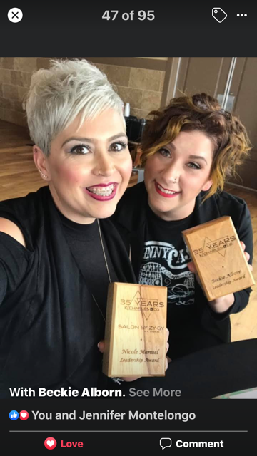 Two smiling women holding wooden plaques, one with short grey hair and the other with brown hair, inside a building. - K. Charles & Co. in San Antonio and Schertz, TX