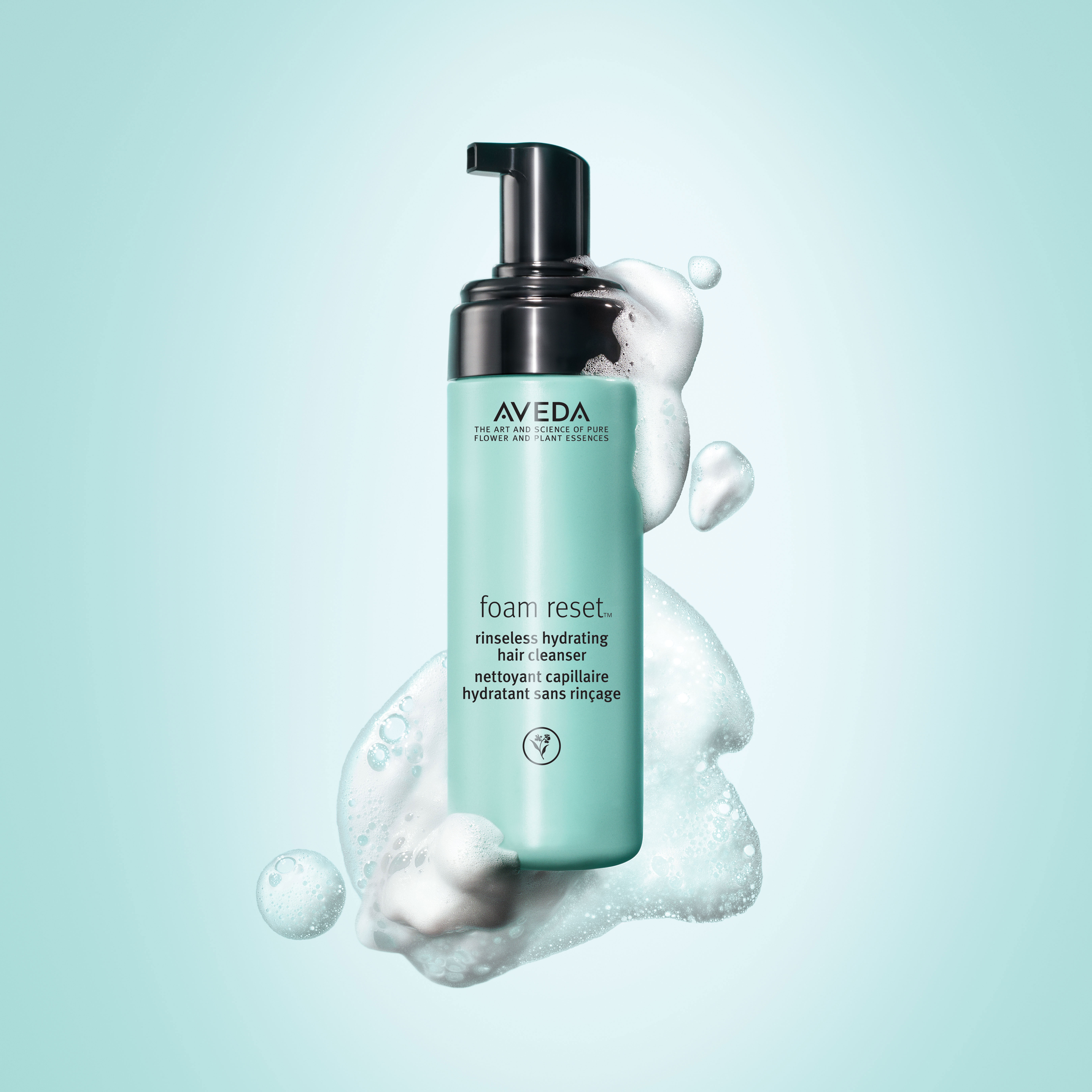 A bottle of aveda foam reset hair cleanser surrounded by bubbles on a teal background. - K. Charles & Co. in San Antonio and Schertz, TX