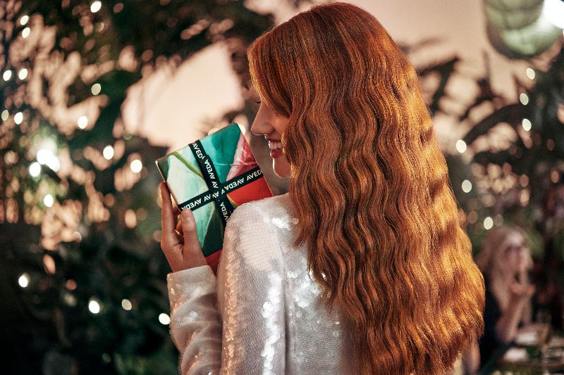 Woman with long red hair reading a book at a festive party, surrounded by greenery and soft lighting. - K. Charles & Co. in San Antonio and Schertz, TX