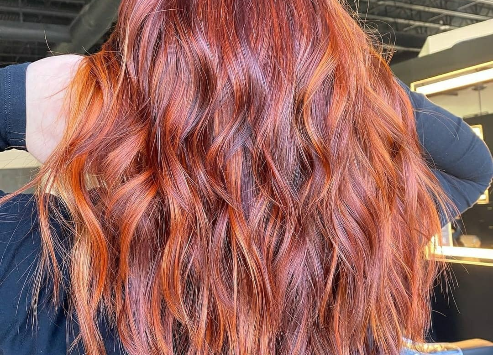 Vibrant copper-red hairstyle with loose curls viewed from behind. - K. Charles & Co. in San Antonio and Schertz, TX