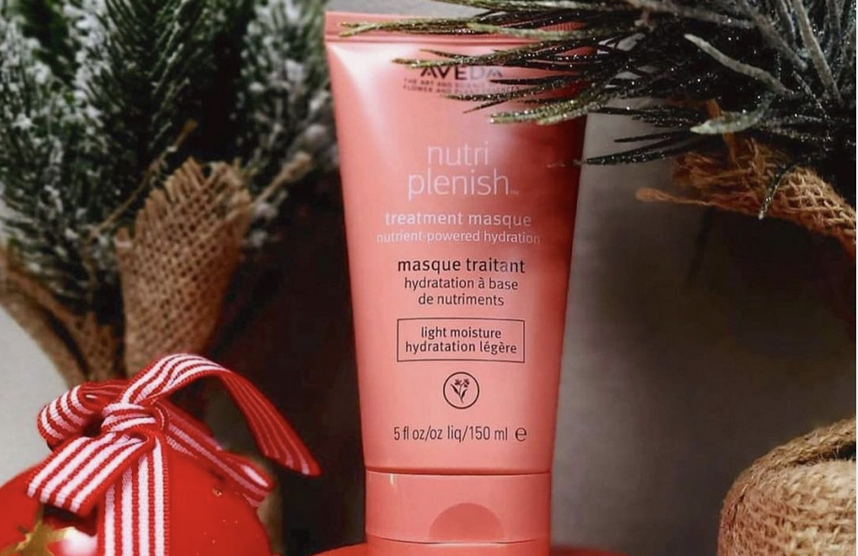 Aveda nutriplenish treatment masque tube beside a Christmas ornament and pine branches, promoting holiday hair color. - K. Charles & Co. in San Antonio and Schertz, TX