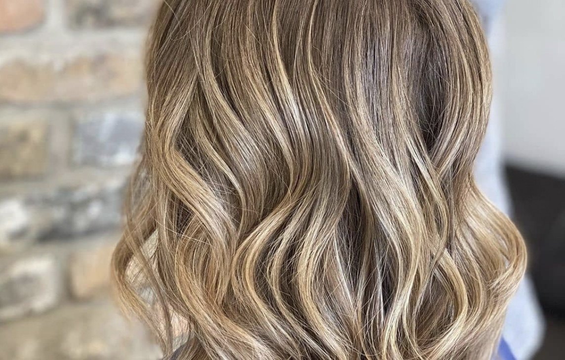 Close-up of a woman's hairstyle showcasing soft, cascading curls with blended brunette and blonde highlights. - K. Charles & Co. in San Antonio and Schertz, TX