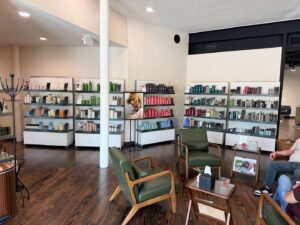 A salon waiting area with green chairs, a coffee table, and shelves displaying various hair care products against the walls. - K. Charles & Co. in San Antonio, TX